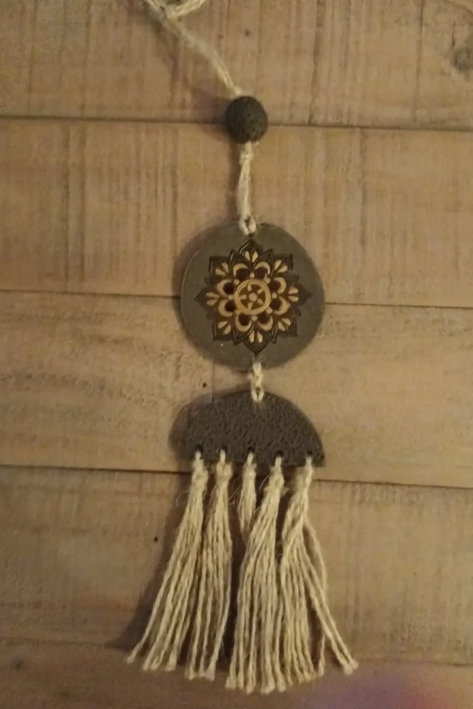 Suspension décorative en grès noir, motif rosace dorée et marron, pompons en ficelle de jute, Isabelle Morales