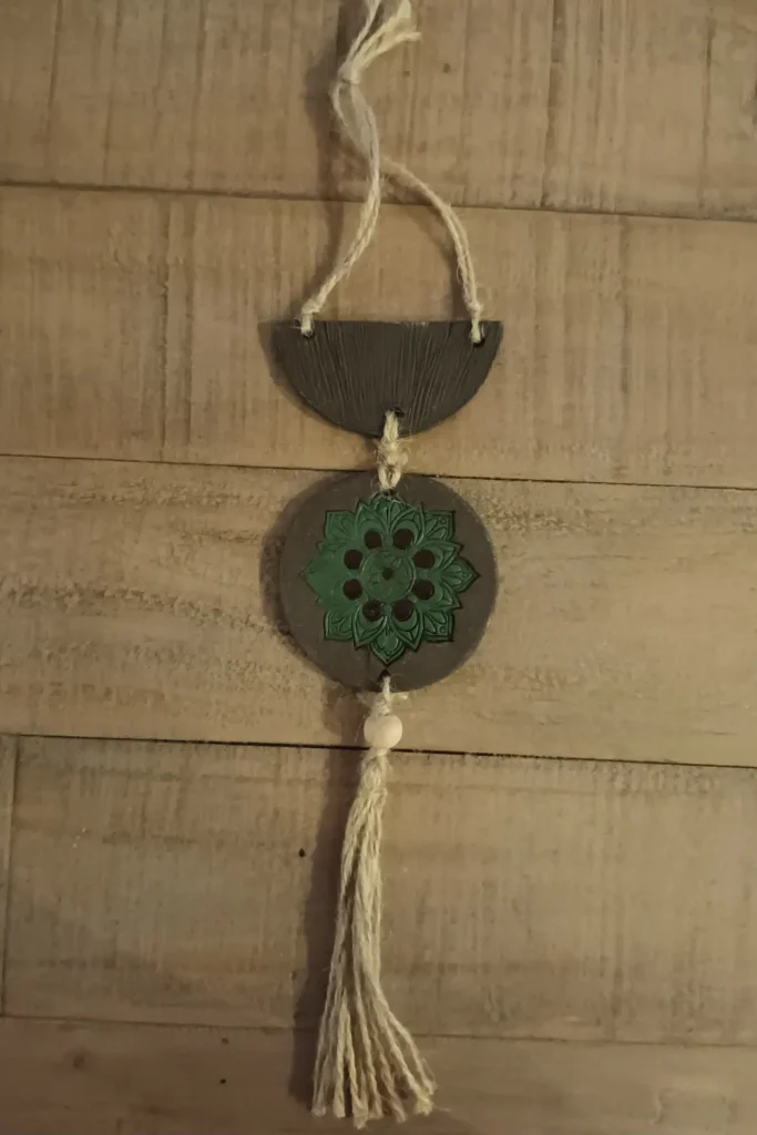 Suspension décorative artisanale en grès noir, motif rosace verte et marron, pompons en ficelle de jute, Isabelle Morales